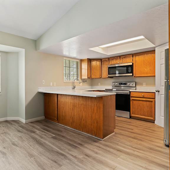an empty kitchen with a large window and wooden cabinets
