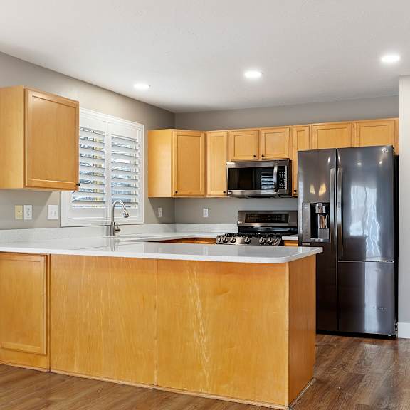a kitchen with wooden cabinets and a black refrigerator.
