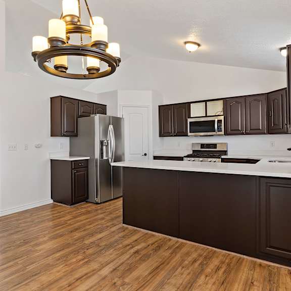 a kitchen with dark brown cabinets and a wooden floor.