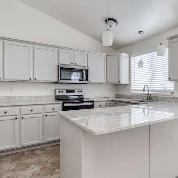 a kitchen with white cabinets and a marble countertop.