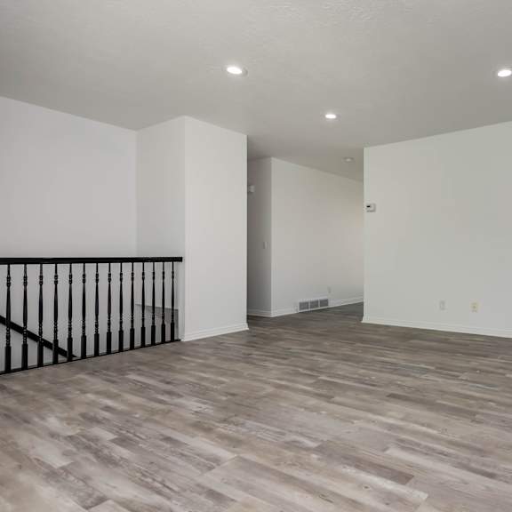 a spacious room with wooden flooring and white walls.