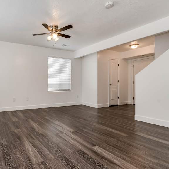 an empty living room with white walls and a ceiling fan