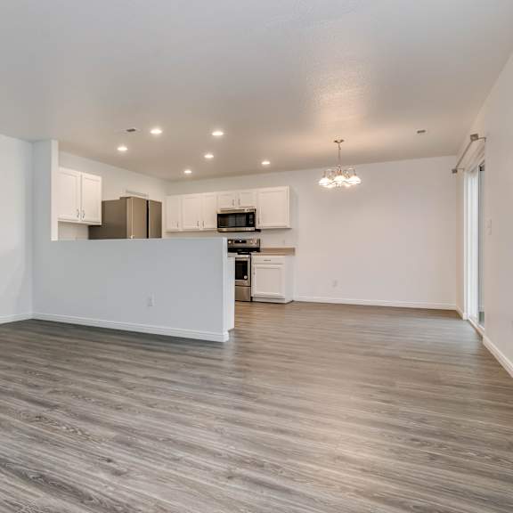 a spacious room with wooden flooring and white walls.