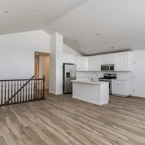 the living room and kitchen of an apartment with white cabinets and wood floors