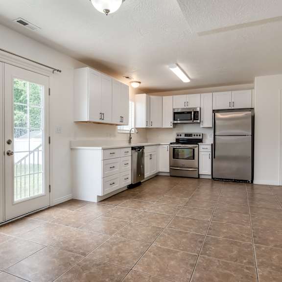 an empty kitchen with stainless steel appliances and white cabinets
