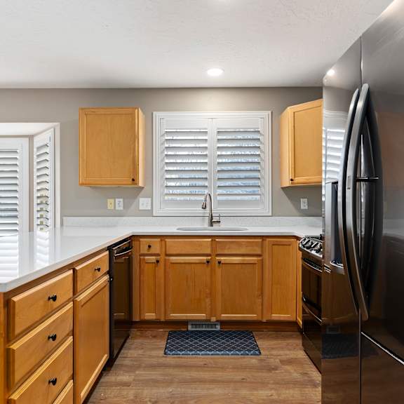 a kitchen with wooden cabinets and a black refrigerator.