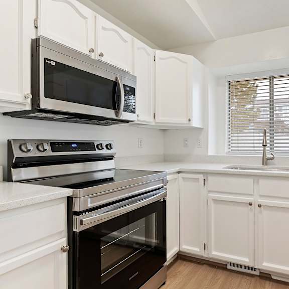 a kitchen with white cabinets and black appliances.
