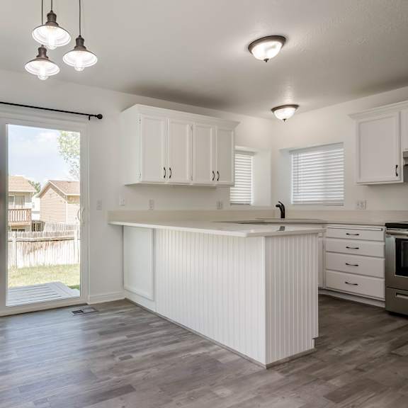 a kitchen with white cabinets and a wooden floor.