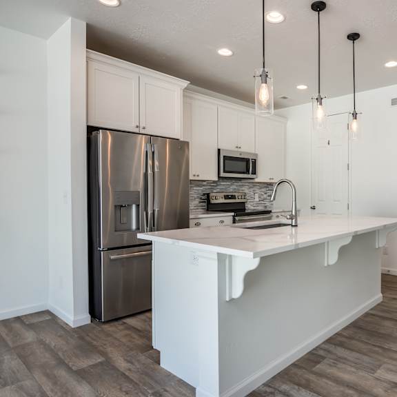 a kitchen with a white island and stainless steel appliances.