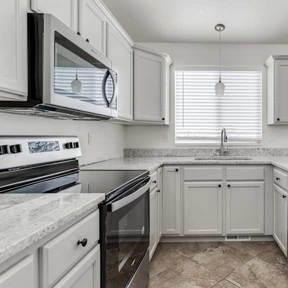 a kitchen with white cabinets and a marble countertop.