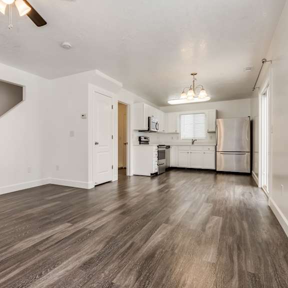 an empty living room and kitchen with white walls and wood floors