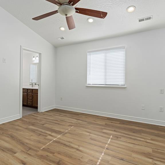 a room with a ceiling fan and wooden flooring.