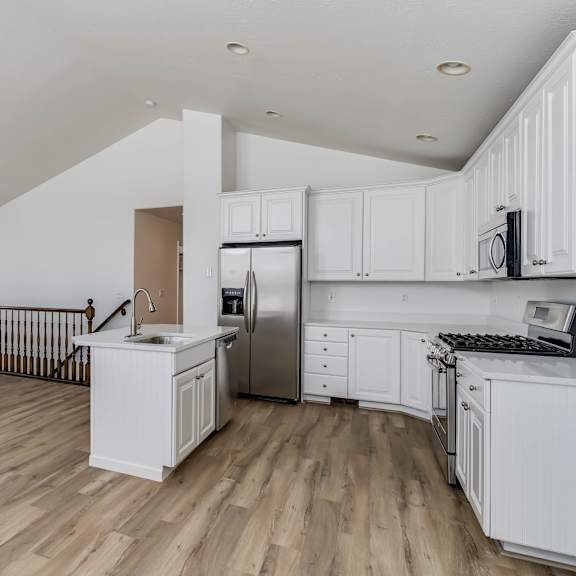 an open kitchen with white cabinets and a wooden floor