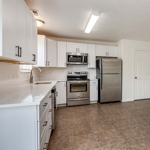 an empty kitchen with stainless steel appliances and white cabinets