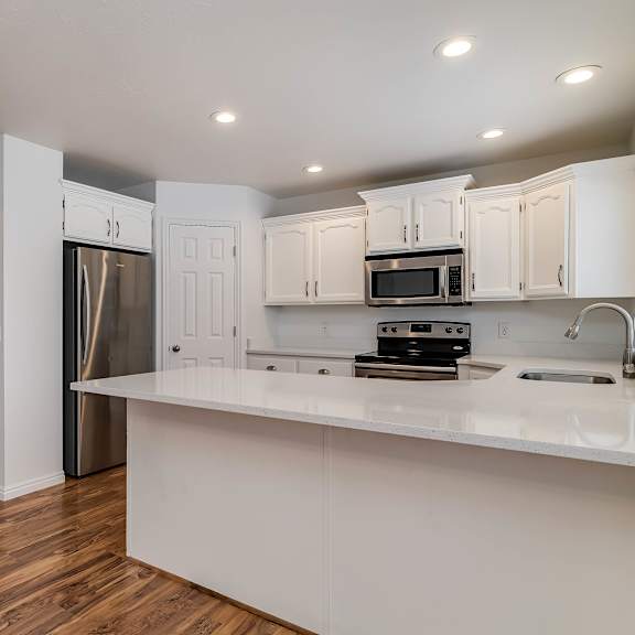 a kitchen with white cabinets and a wooden floor.