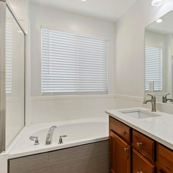 a modern bathroom with a white tub, sink, and mirror.