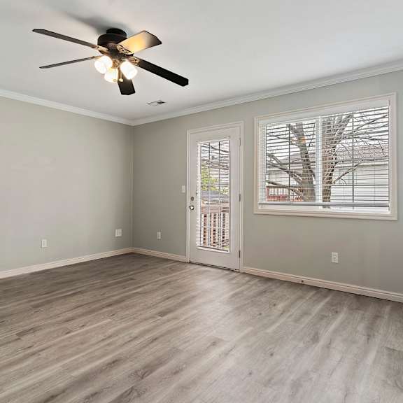 an empty living room with a ceiling fan and a window