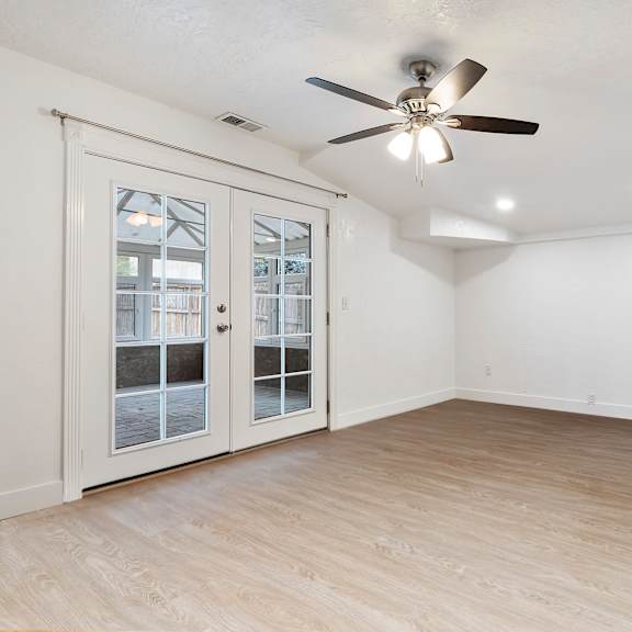 a room with a ceiling fan and sliding glass doors.