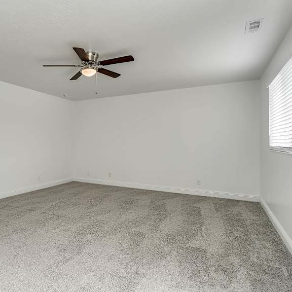 a room with a ceiling fan and carpeted floor.