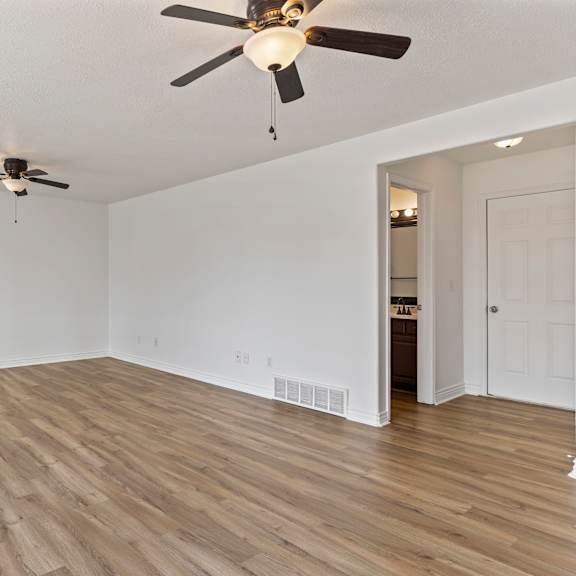 a room with a ceiling fan and wooden flooring.