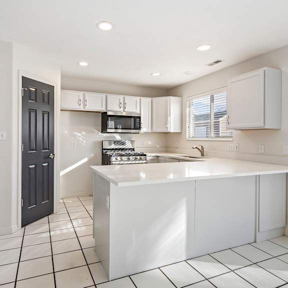 an open kitchen with white cabinets and a white counter top