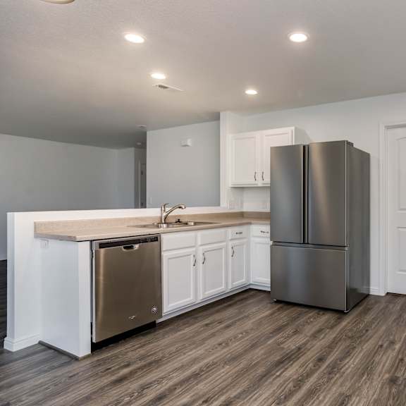 a kitchen with white cabinets and a wooden floor.