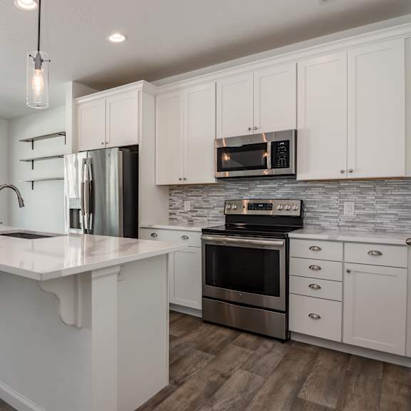a modern kitchen with white cabinets and a wooden floor.