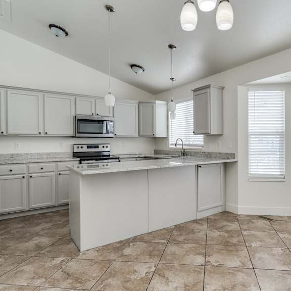a kitchen with a white countertop and a microwave on it.