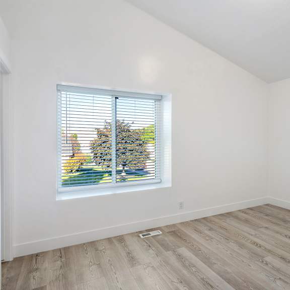 an empty room with white walls and a window with blinds