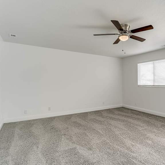 a room with a ceiling fan and carpeted floor.
