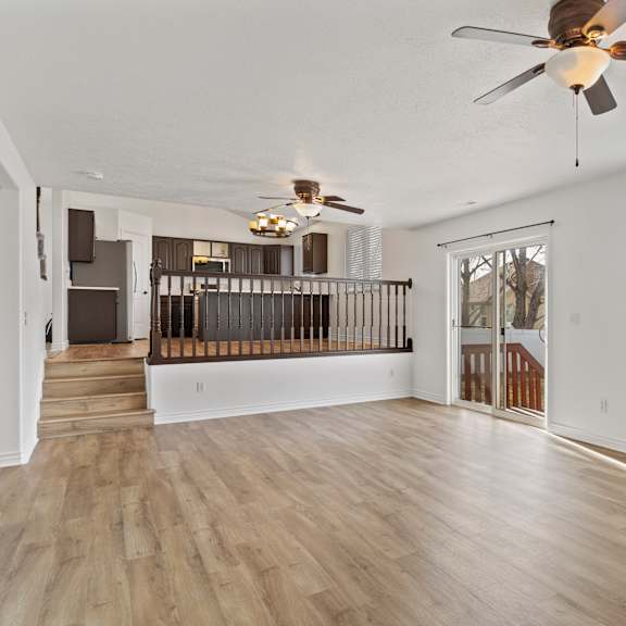 a room with a ceiling fan and wooden flooring.
