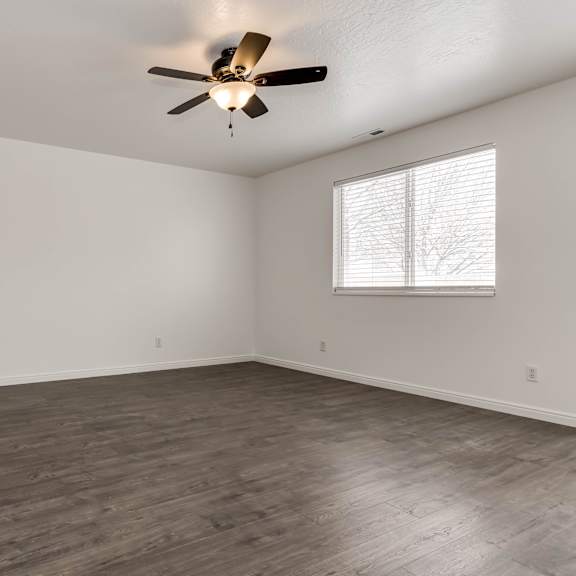 a room with a ceiling fan and a window with blinds.
