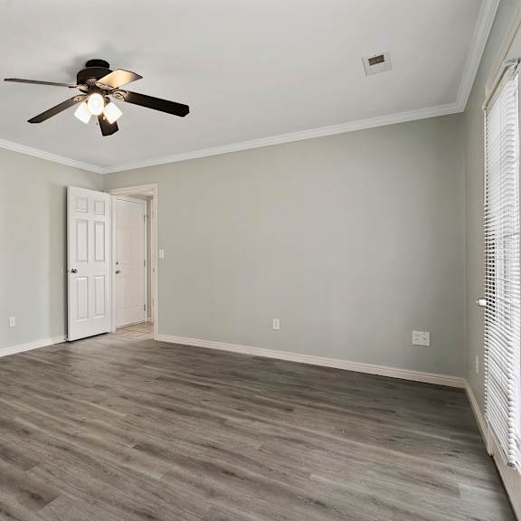 an empty living room with a ceiling fan and a door