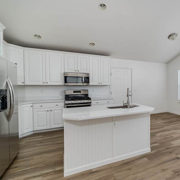 an open kitchen with white cabinets and a large window