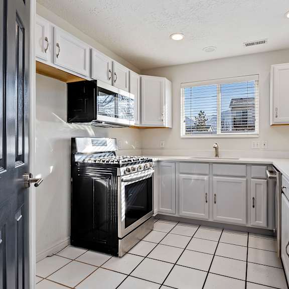 an empty kitchen with white cabinets and a black stove and refrigerator