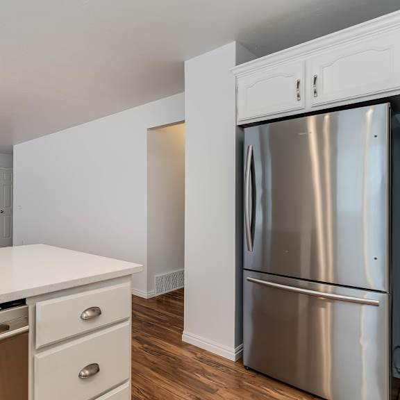 a modern kitchen with a stainless steel refrigerator and white countertops.
