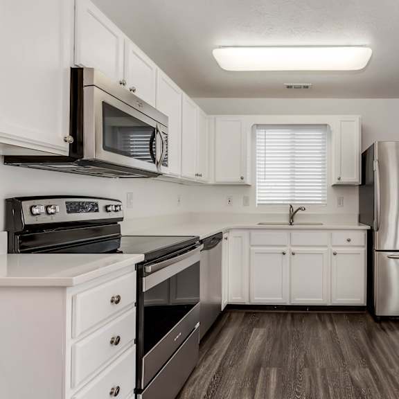an empty kitchen with white cabinets and stainless steel appliances