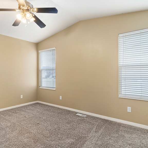 a room with a ceiling fan and carpeted floor.