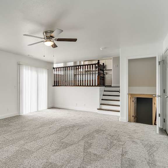 a spacious room with a ceiling fan and carpeted floor.