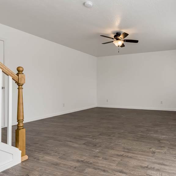 a room with a ceiling fan and wooden flooring.