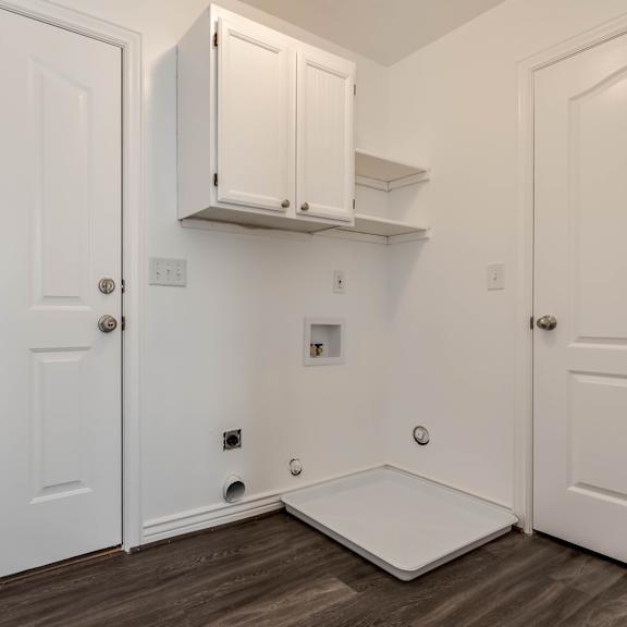 an empty room with white walls and wood flooring and a white door