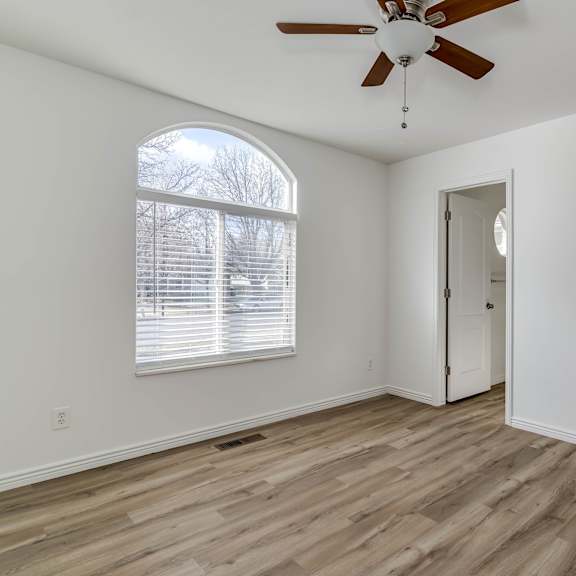 an empty living room with white walls and a ceiling fan