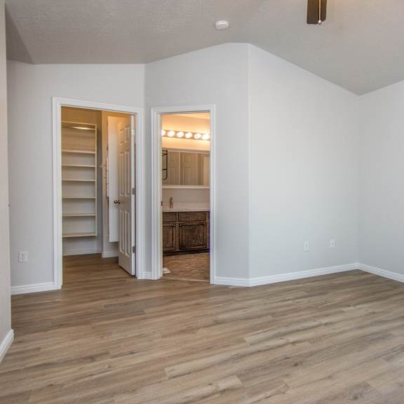 an empty living room with wooden floors and white walls