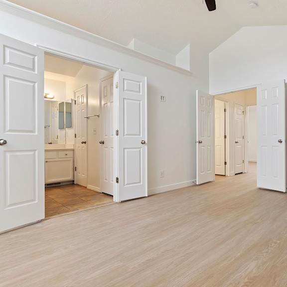 a room with white walls and wooden flooring with a ceiling fan.