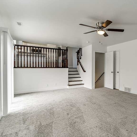 a spacious room with a ceiling fan and carpeted floor.