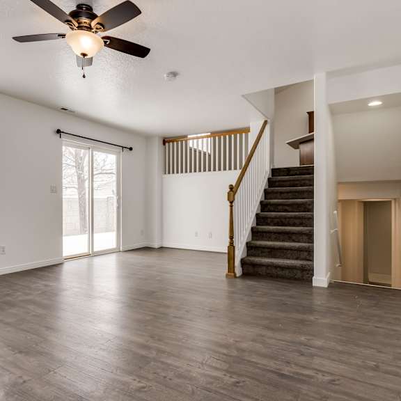 a spacious room with a ceiling fan and wooden flooring.