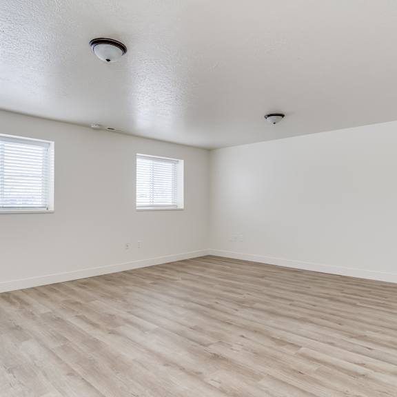 a room with wooden flooring and two windows.
