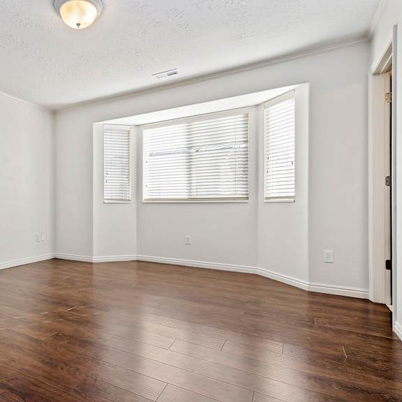 an empty living room with wood floors and a window