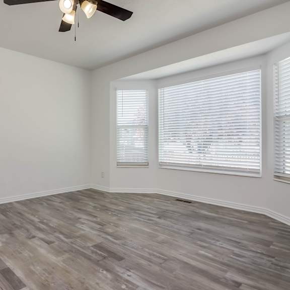 a room with a ceiling fan and wood flooring.