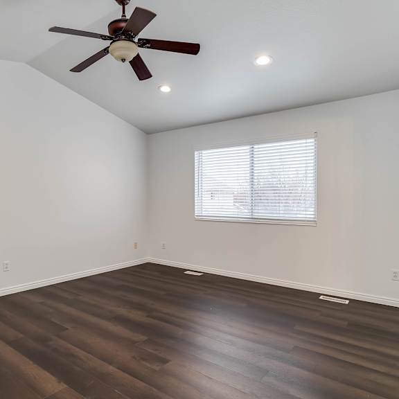 a room with a ceiling fan and wooden flooring.